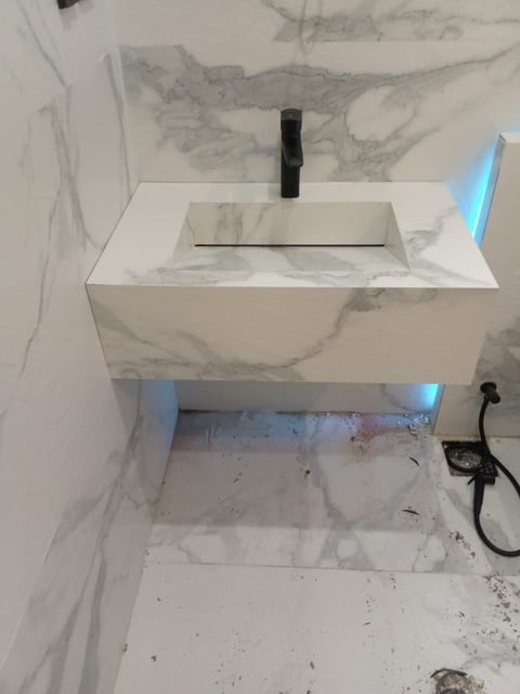 Modern white rectangular bathroom sink with black faucet mounted on marble-textured wall