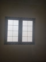 Two-pane gray window divided into eight sections on a dark wall