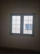 Two gray-framed windows with white panes set in a beige wall