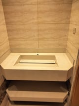 Modern bathroom with a built-in beige bathtub surrounded by tan tile walls and stepped platform base