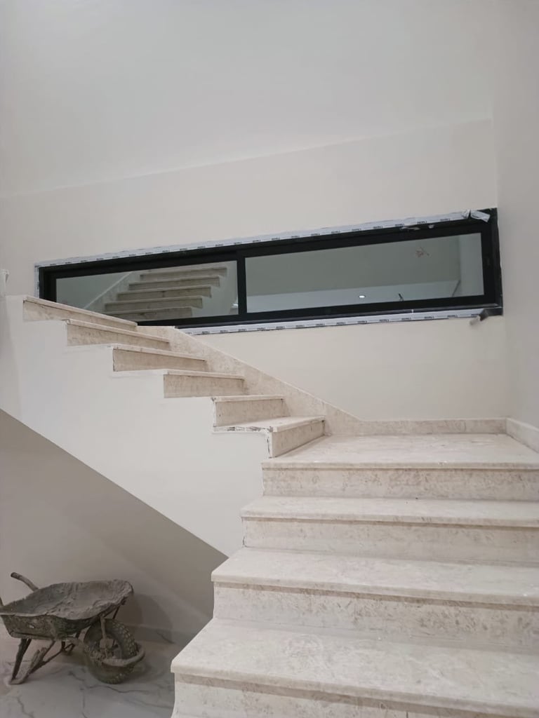 Stack of metal-framed window or door frames with dark glass panels in an empty room